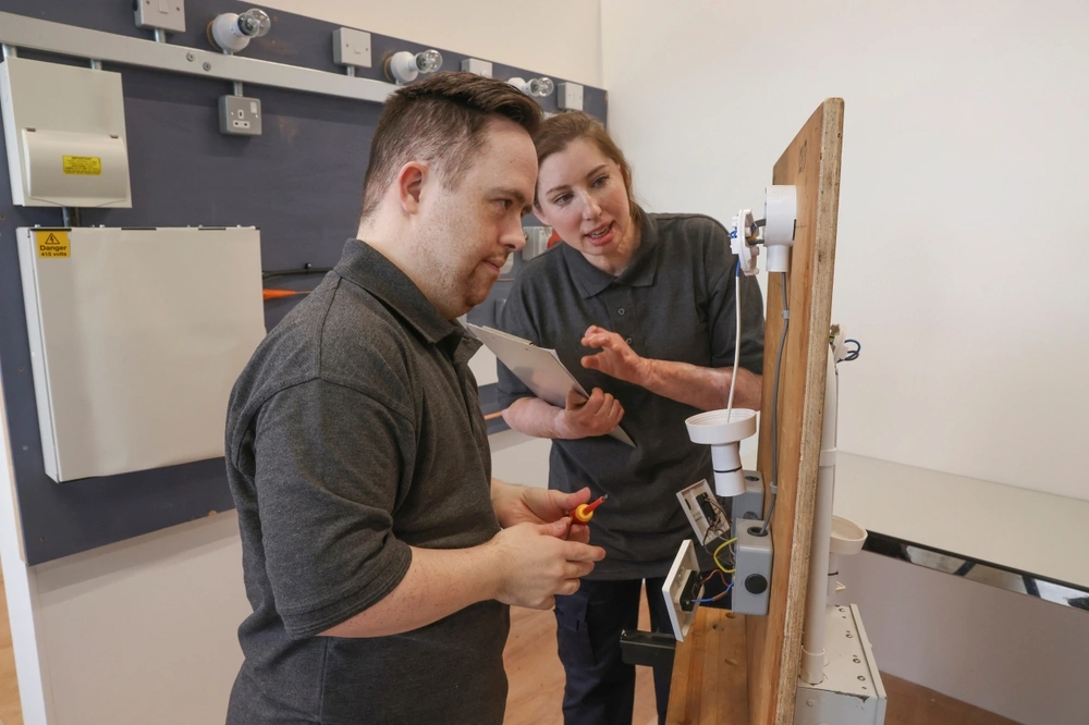 down syndrome person working as an electrician with instructor